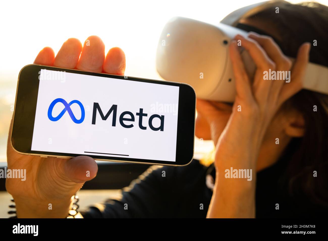 Meta logo on the iPhone, rebranding. Woman holding smartphone with new  facebook logo wearing Oculus VR headset Stock Photo - Alamy