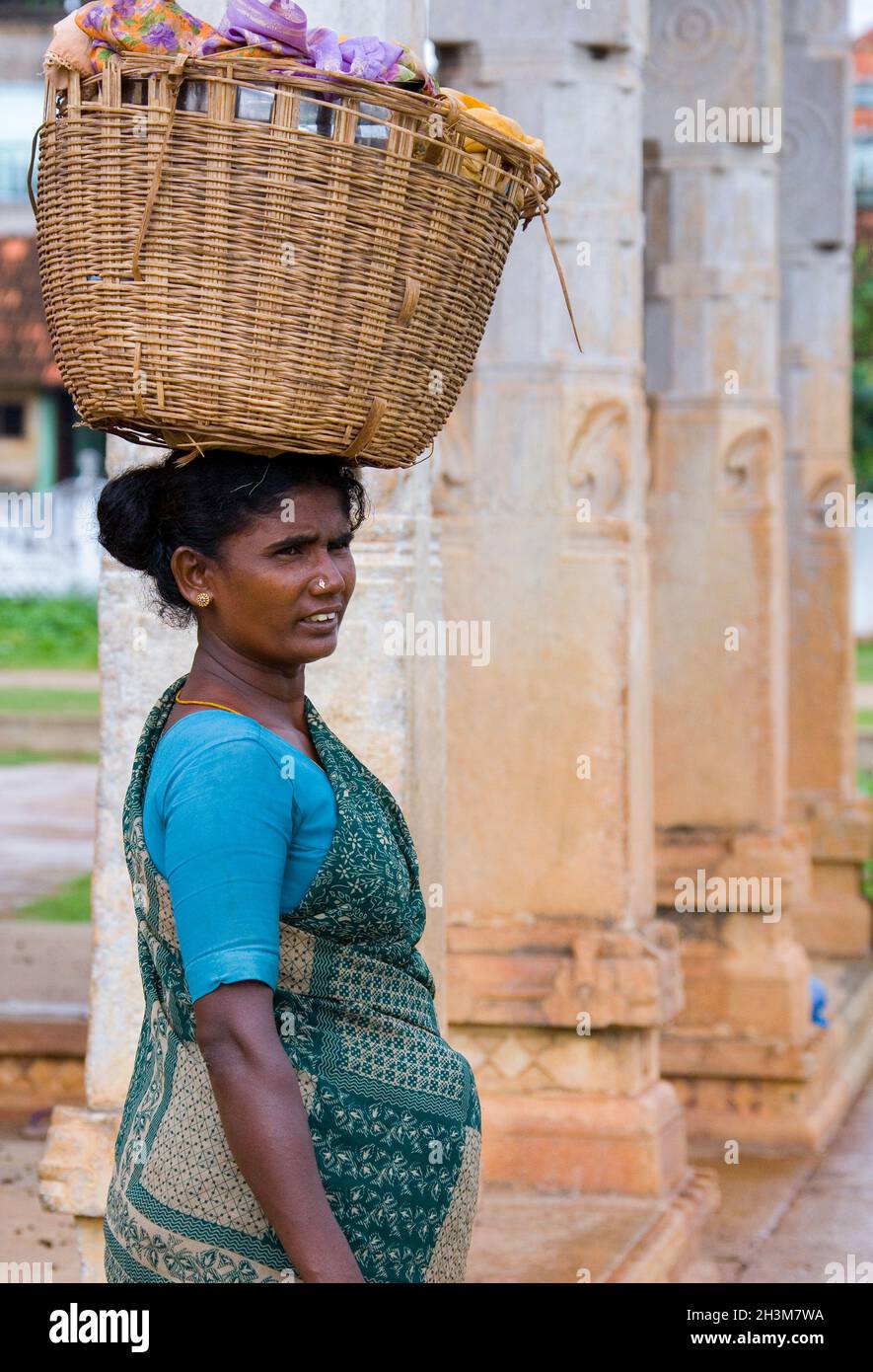 An Indian woman carrying a basket full of washing balanced on her head