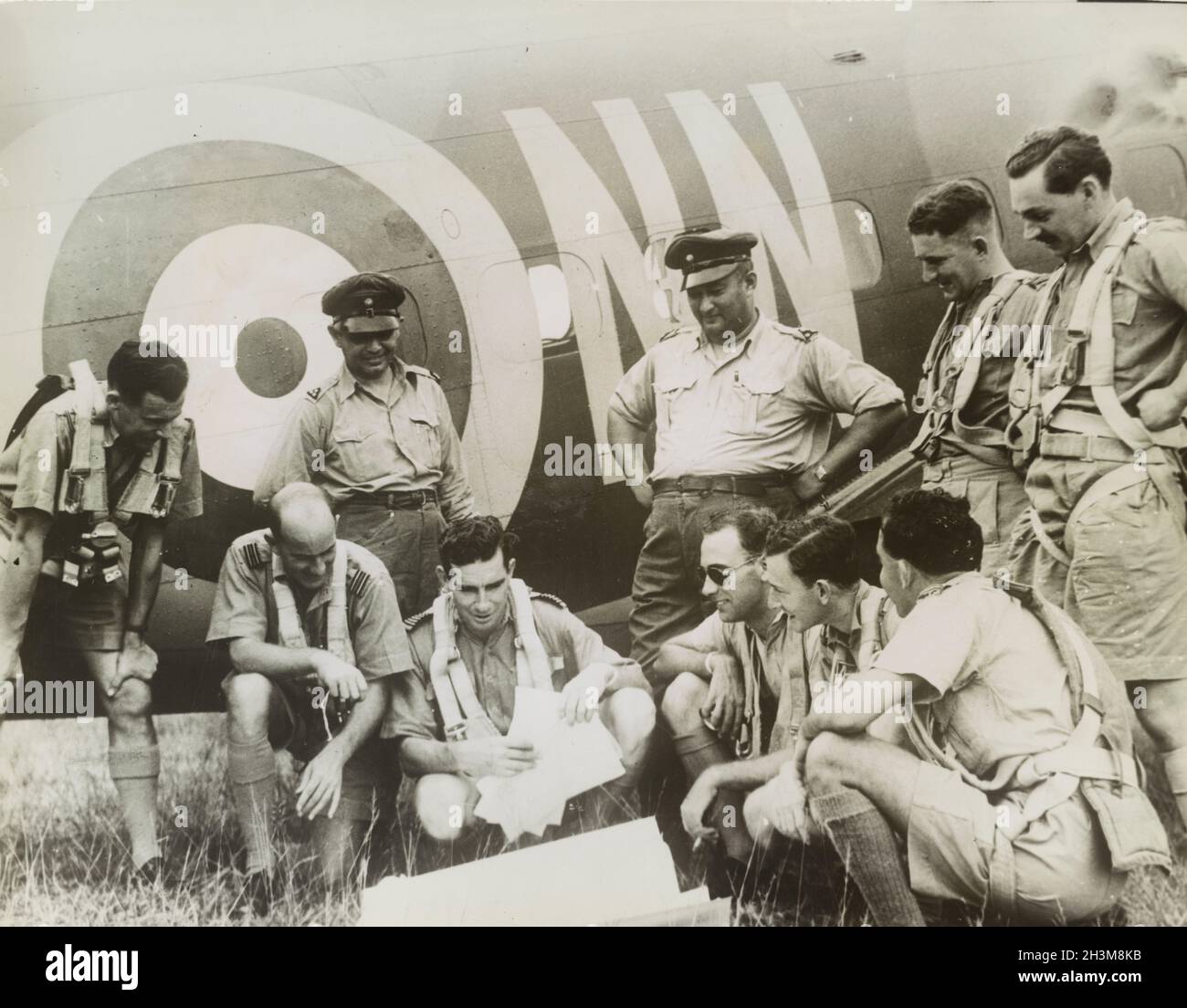 Vintage photo circa 1942 of British RAF and Dutch fighter pilots discussing patrol plans next to an RAF plane during the Japanese invasion of Malaya and the fall of Singapore Stock Photo