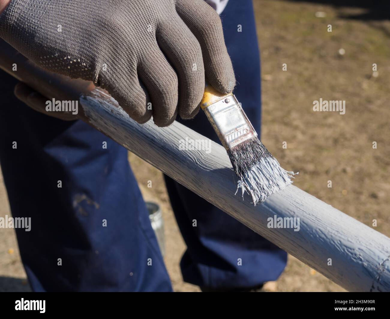 person primer painted metal pipe outdoors Stock Photo