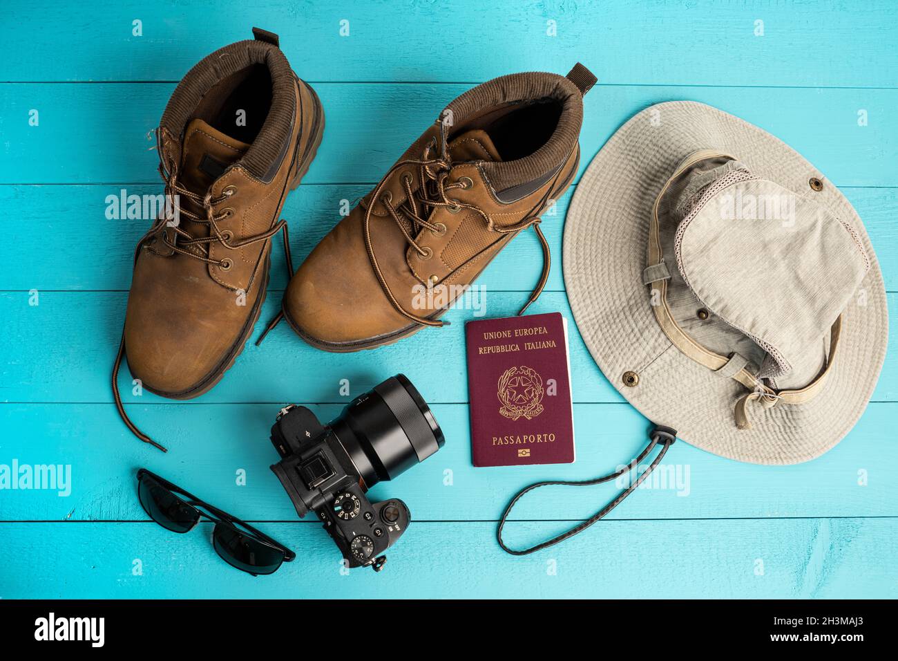A camera, a hat and a pair of shoes on a colored surface Stock Photo