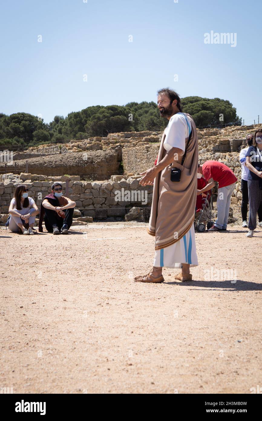 CATALONIA, SPAIN-MAY 8, 2021: Tour guide in authentic antique clothing at Archaeological Remains of ancient city Empuries. Archaeology Museum of Catal Stock Photo