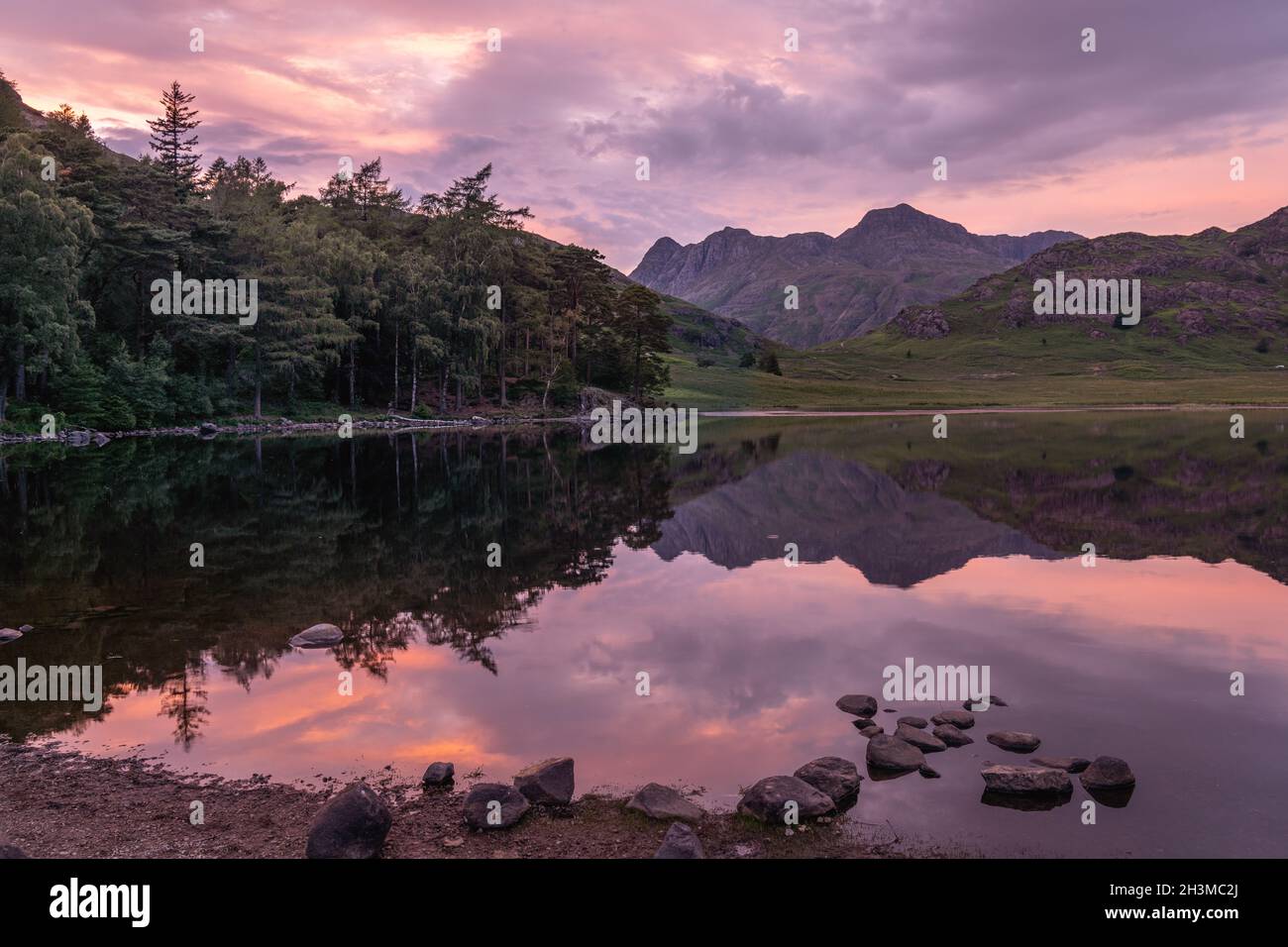 Sunset from Blea Tarn in the Lake District National Park, UK England.  The Langdale Pikes form the mountain backdrop and the sky reflection in the wat Stock Photo