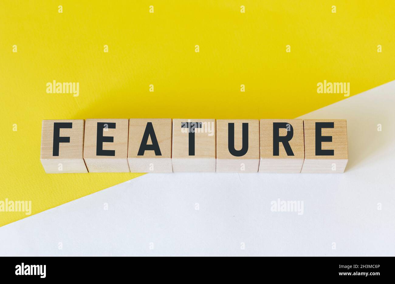 The word FEATURE is composed of building blocks on a white and yellow background. Stock Photo