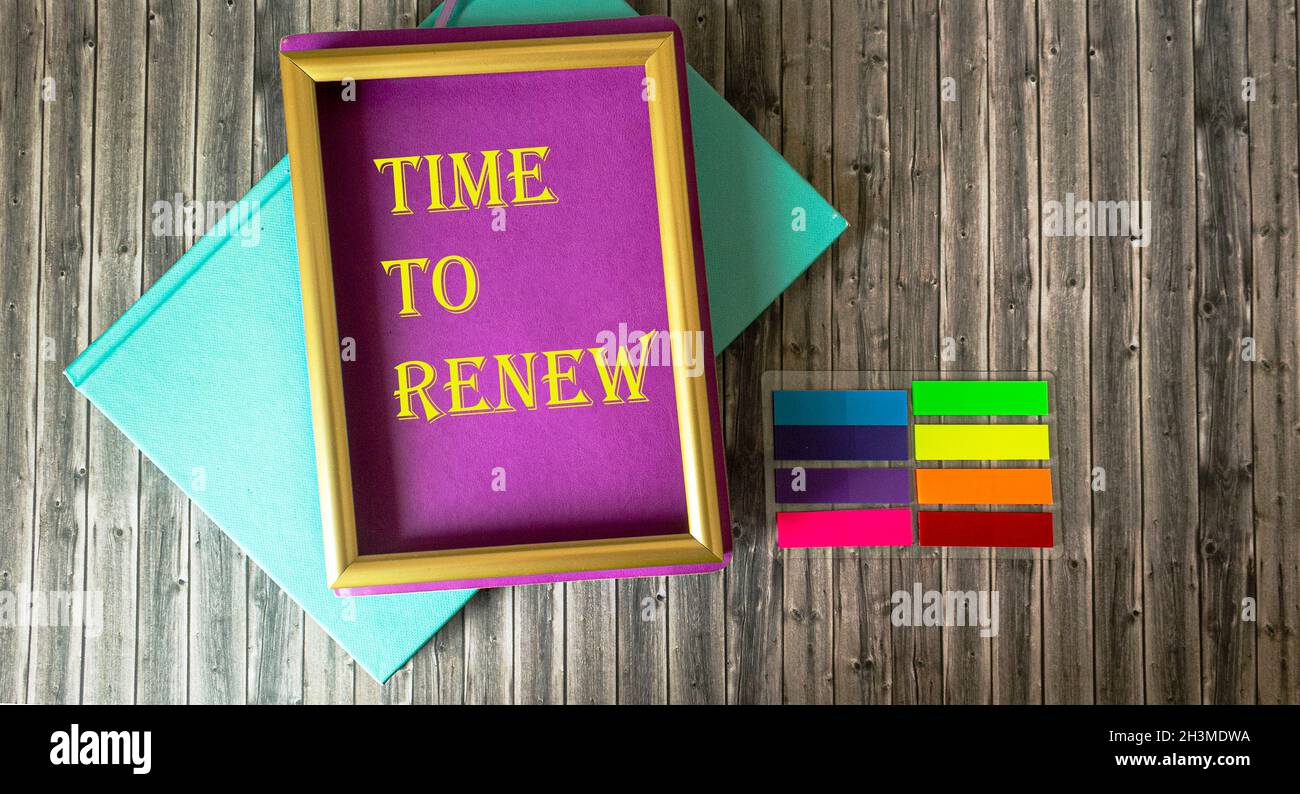 Frame with inscription Time to renew and bright notepads and stickers on wooden table, business concept Stock Photo