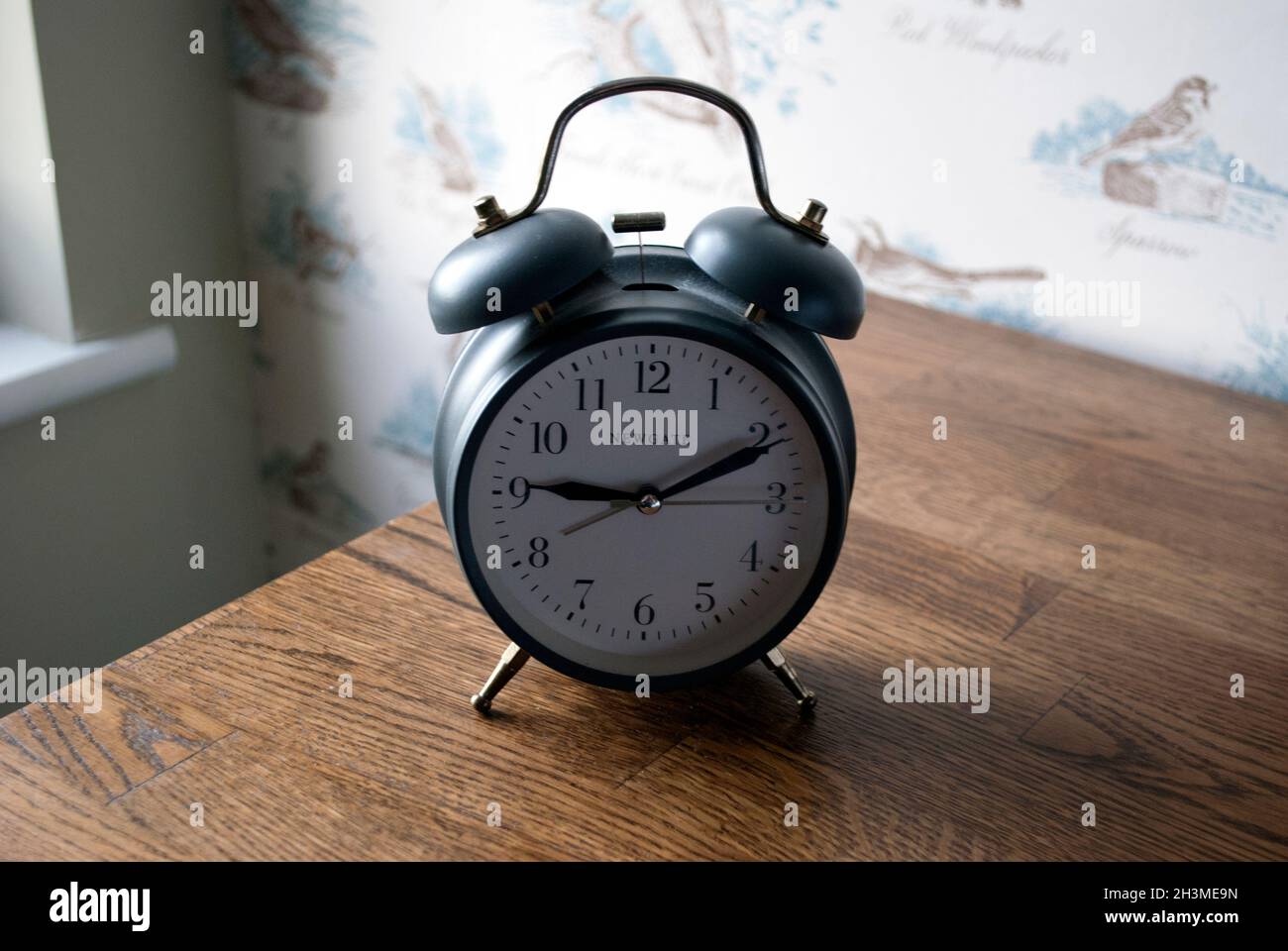 Old fashioned wind up alarm clock on side table in bedroom of pub and