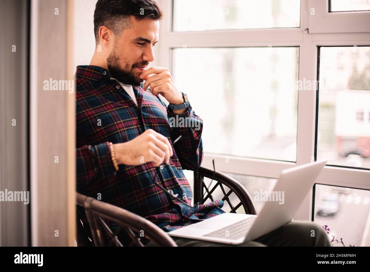 Happy thoughtful man using laptop computer at home Stock Photo