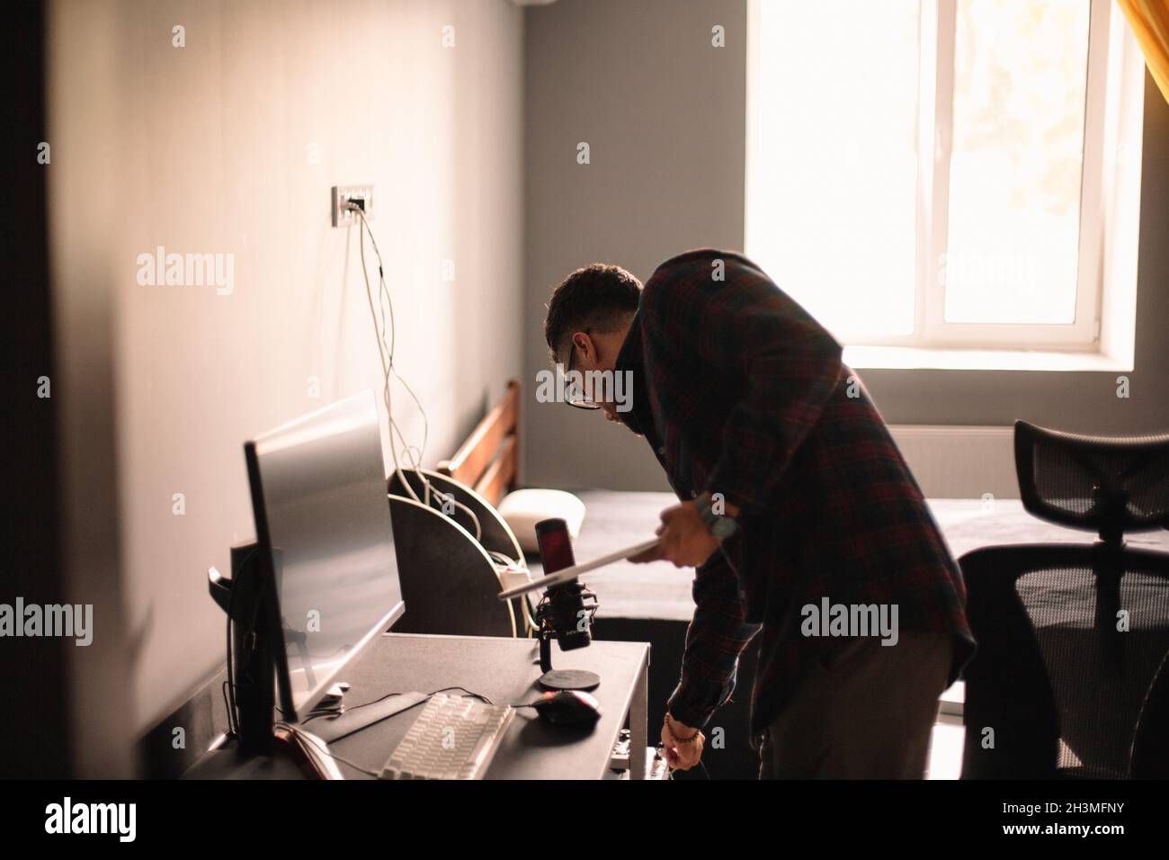 Man holding laptop while standing by desktop computer at home Stock Photo