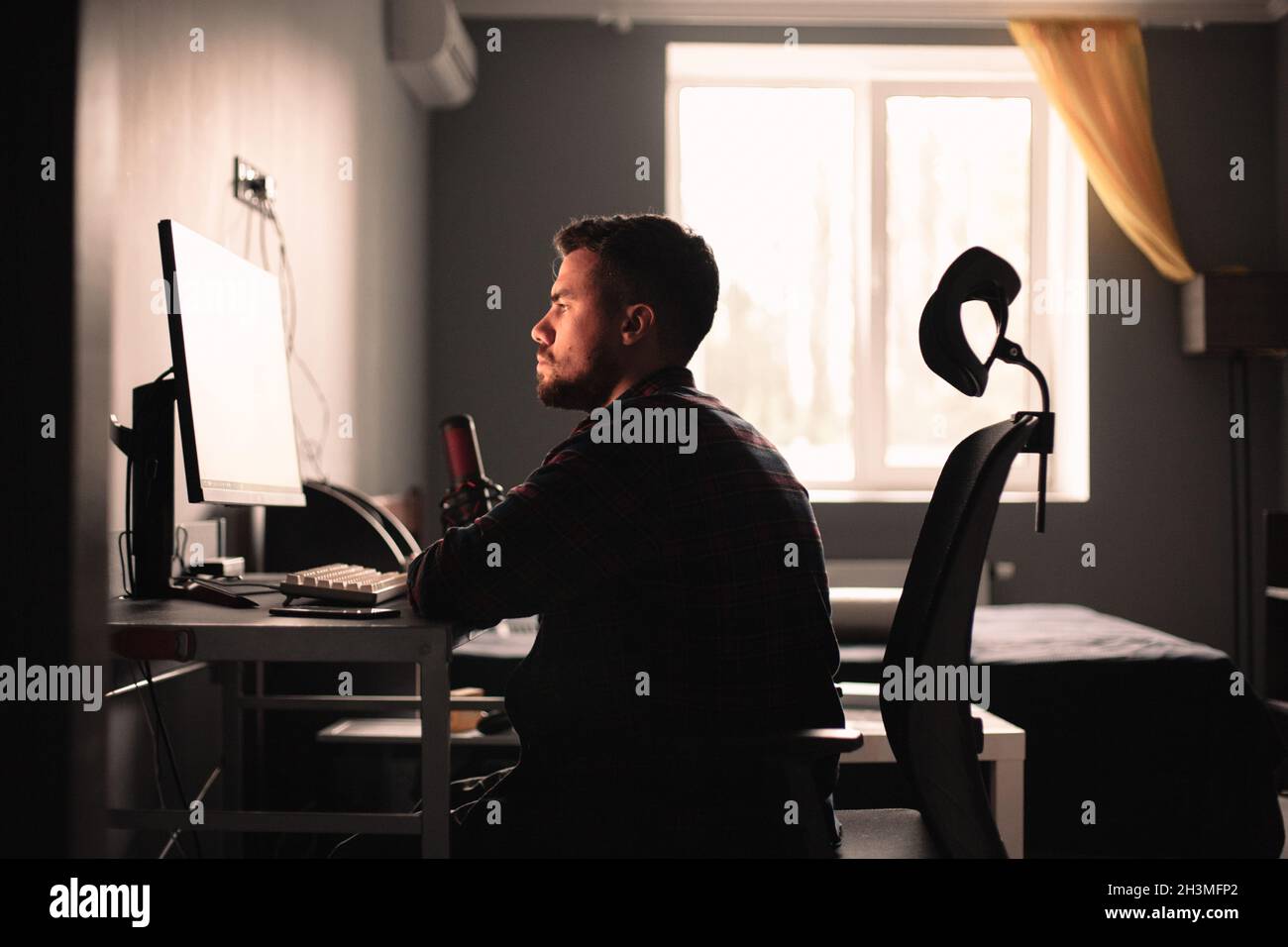 Man sitting at desk working on computer at home Stock Photo