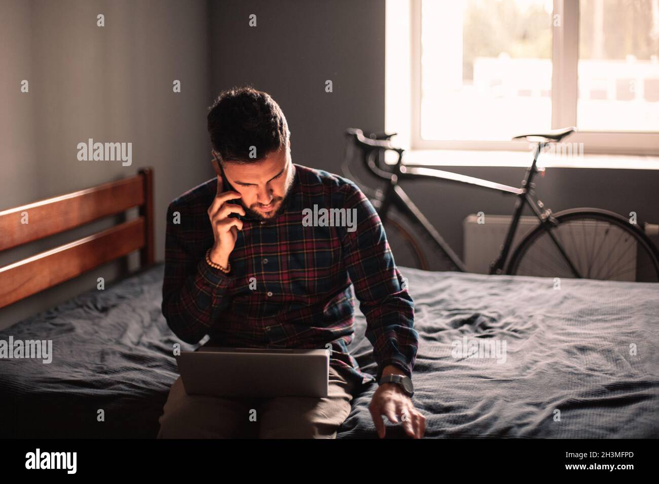 businessman talking on smart phone while using laptop at home Stock Photo