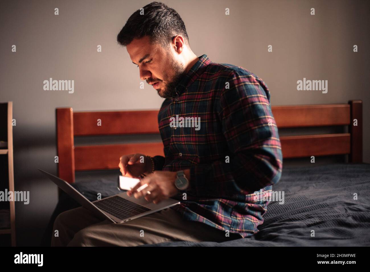 Man using laptop computer and smart phone at home Stock Photo