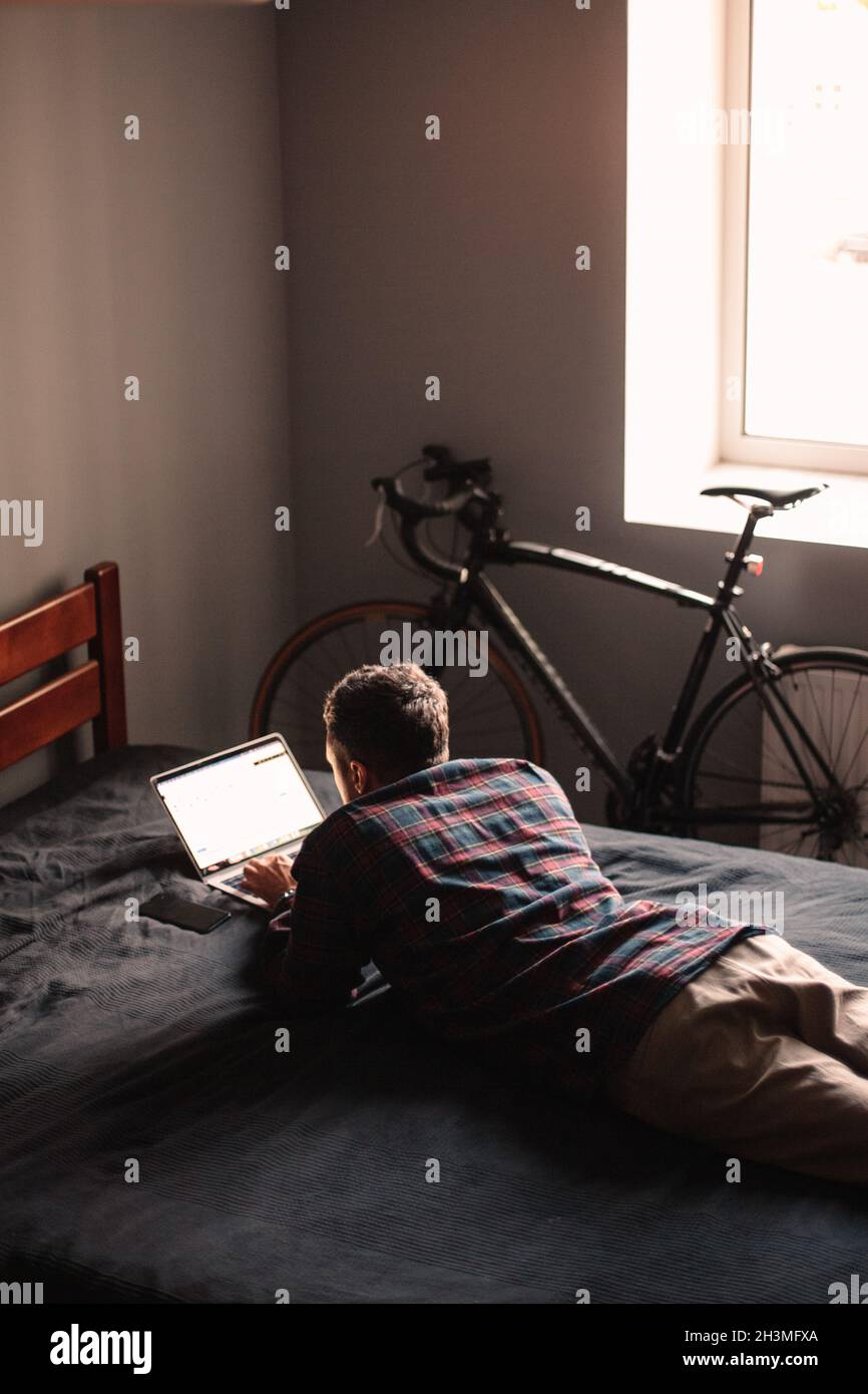 Man using laptop computer lying on bed at home Stock Photo
