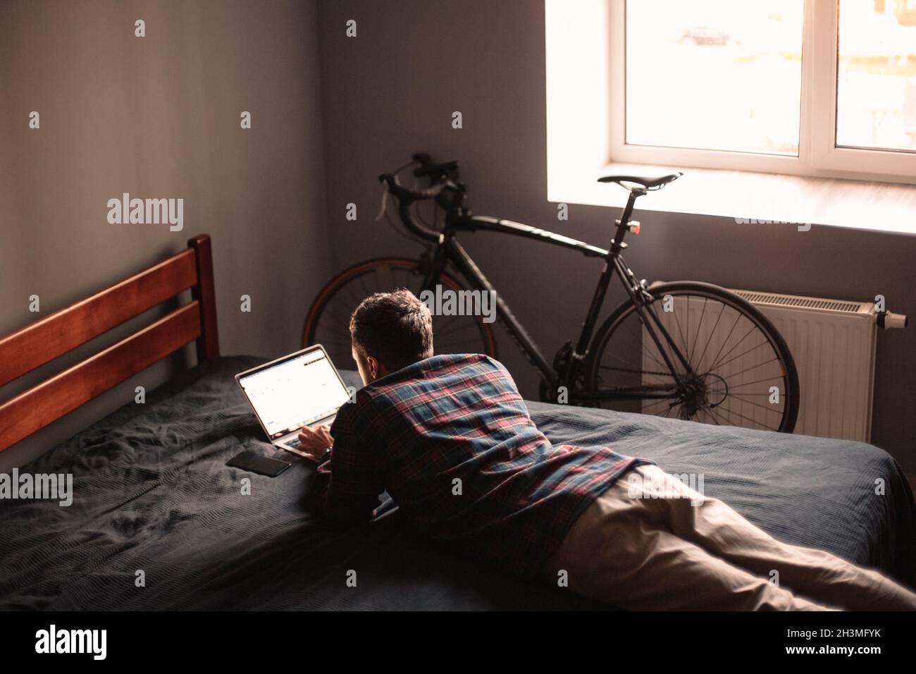 Man using laptop computer lying on bed at home Stock Photo