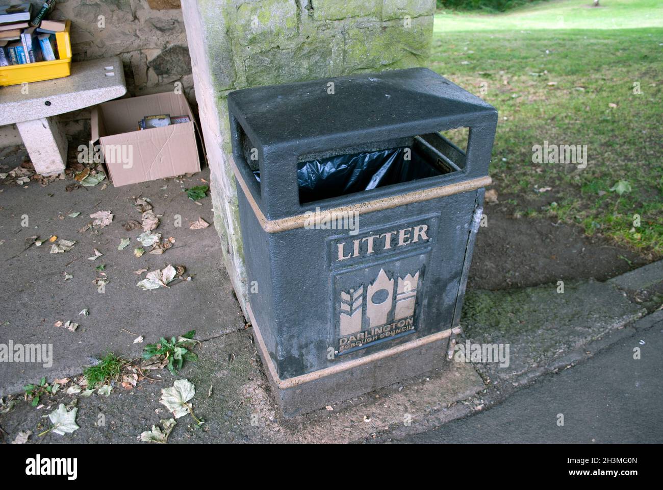 Litter bin outside a free community library in old stone bus shelter