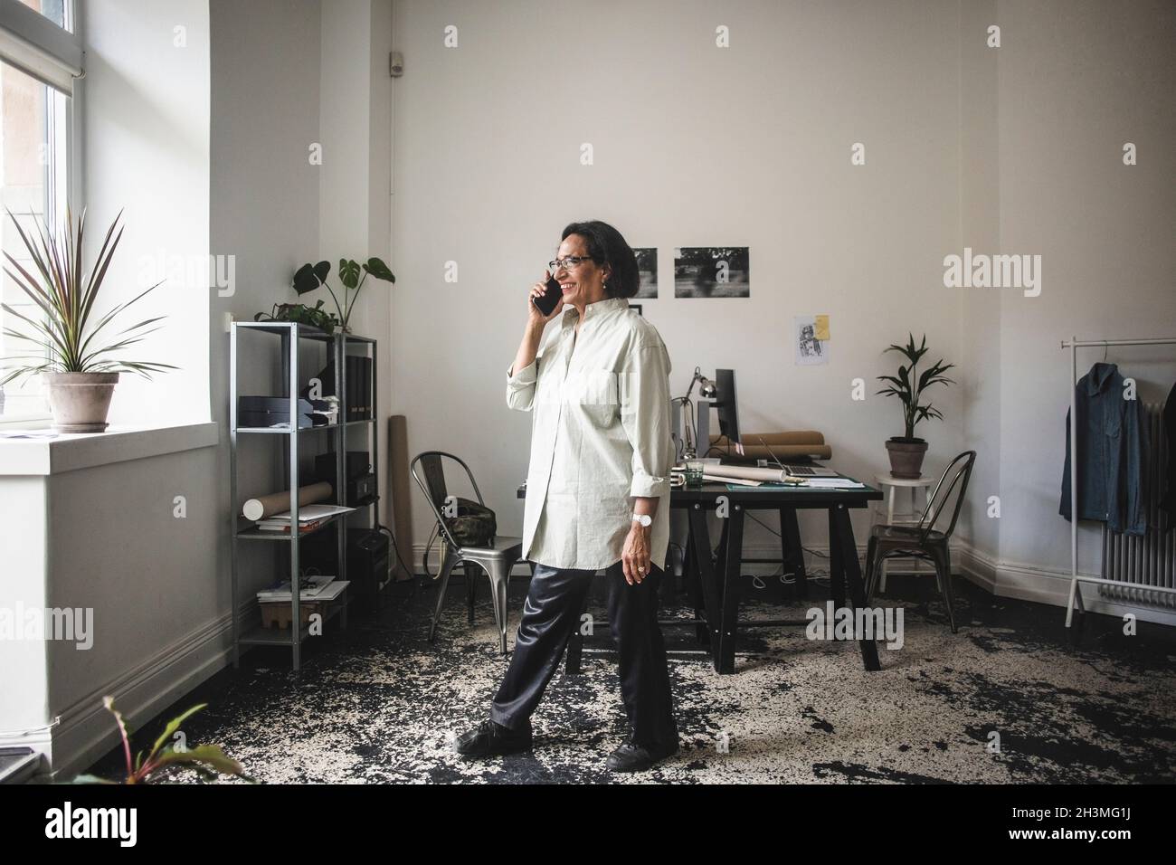 Smiling female owner talking on smart phone at workshop Stock Photo