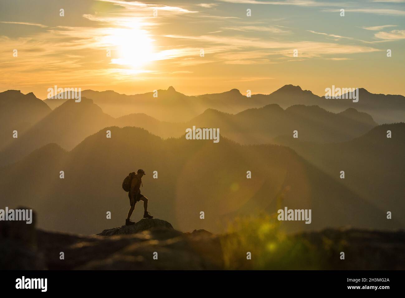 Silhouetted view of backpacker hiking on mountain summit. Stock Photo