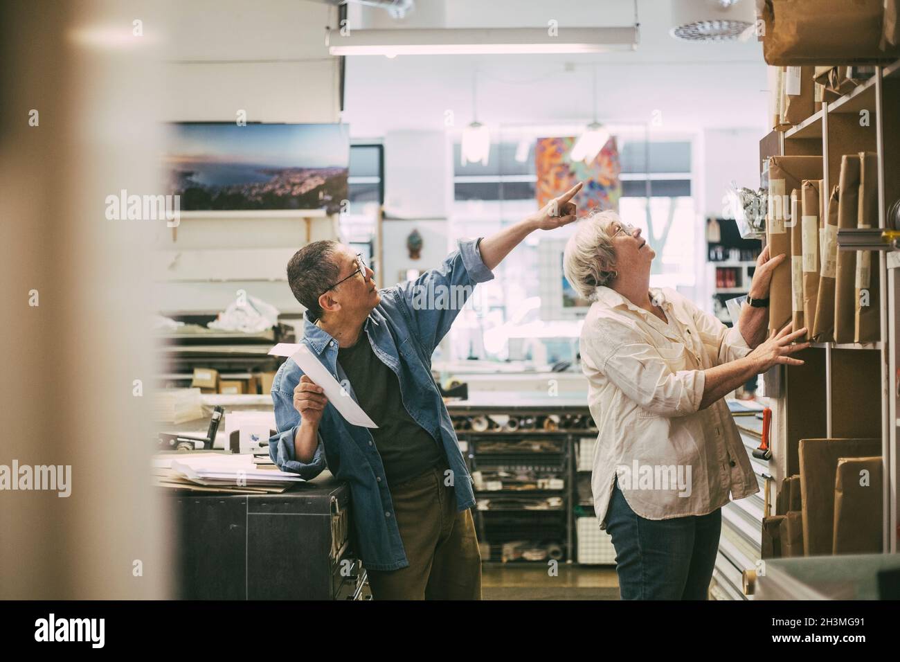 Craftsman pointing while discussing over frames with female coworker at workshop Stock Photo