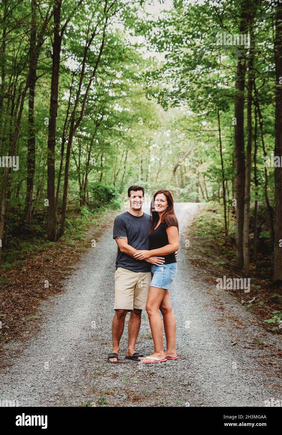 Happy couple embracing on a trail through the woods in summer Stock ...