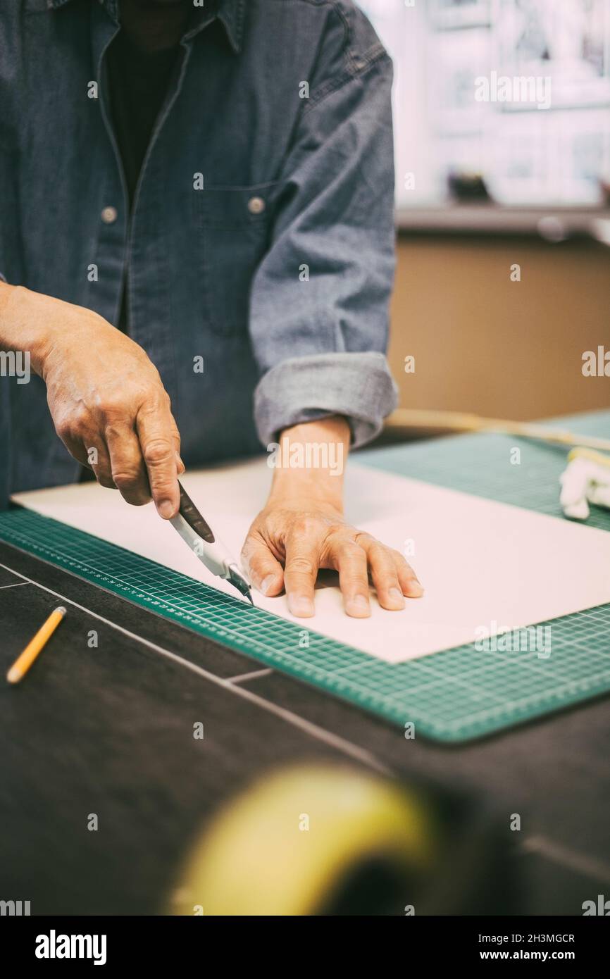 Midsection of male entrepreneur cutting paper at workshop Stock Photo