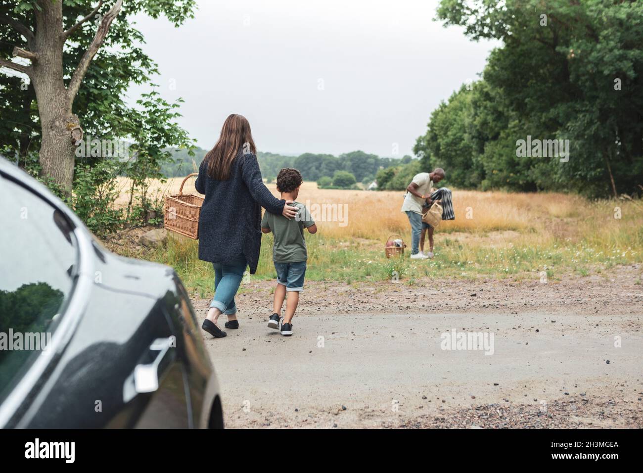 Rear view of woman walking with son towards family during picnic Stock Photo