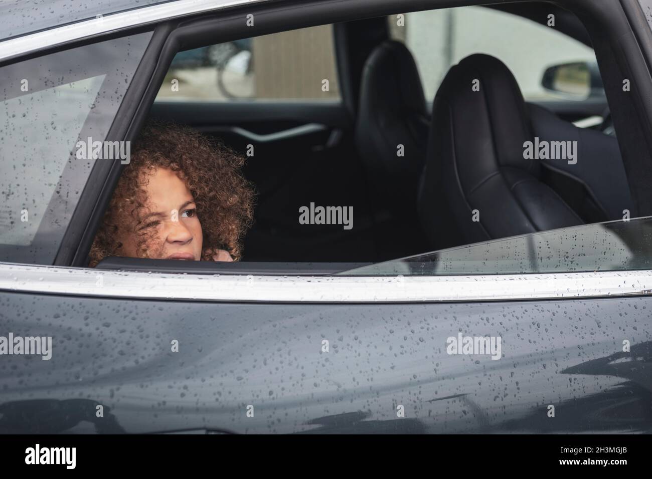 Girl looking through window of car Stock Photo