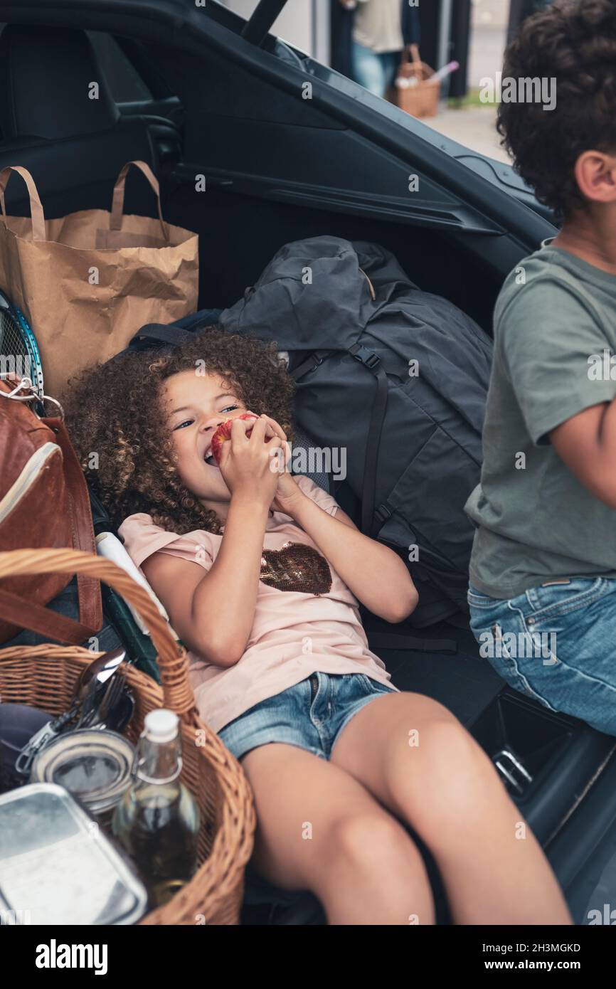 High angle view of girl eating apple by brother in car trunk Stock Photo