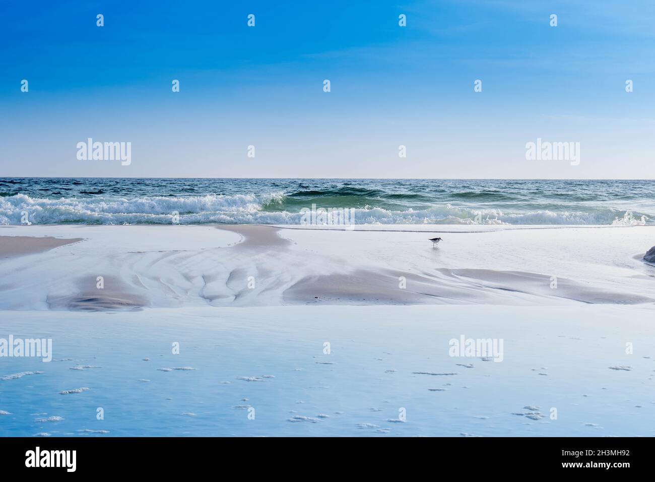 A beautiful sea whitecap waves roll onto the sandy beach of Emerald Coast Stock Photo