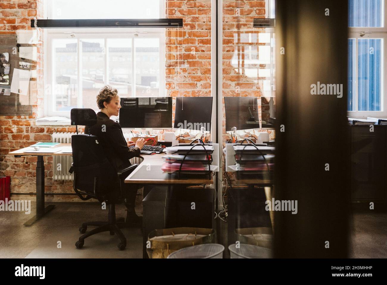 Female manager using laptop while sitting at desk in creative office Stock Photo
