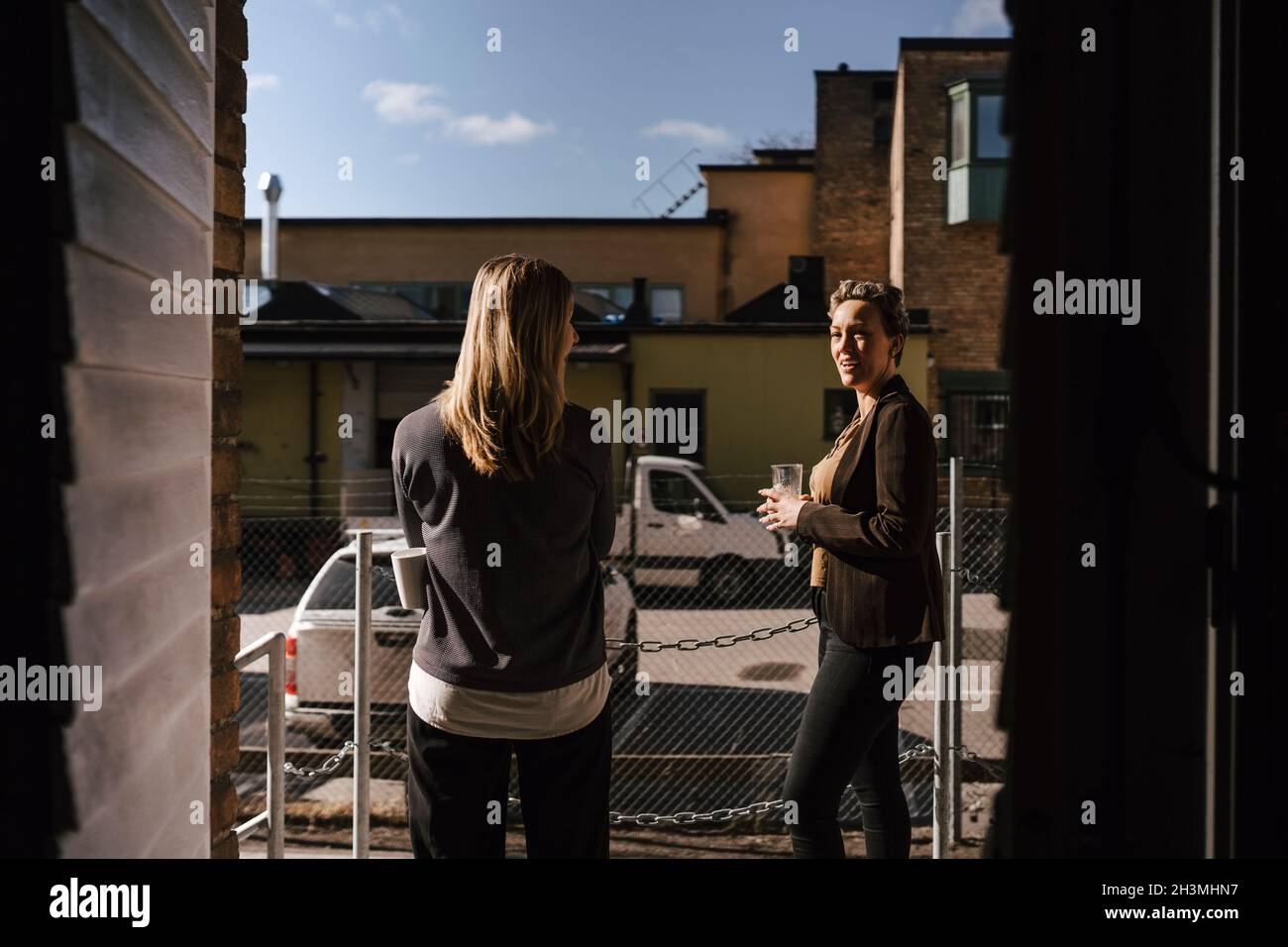 Female business colleagues talking outside office Stock Photo