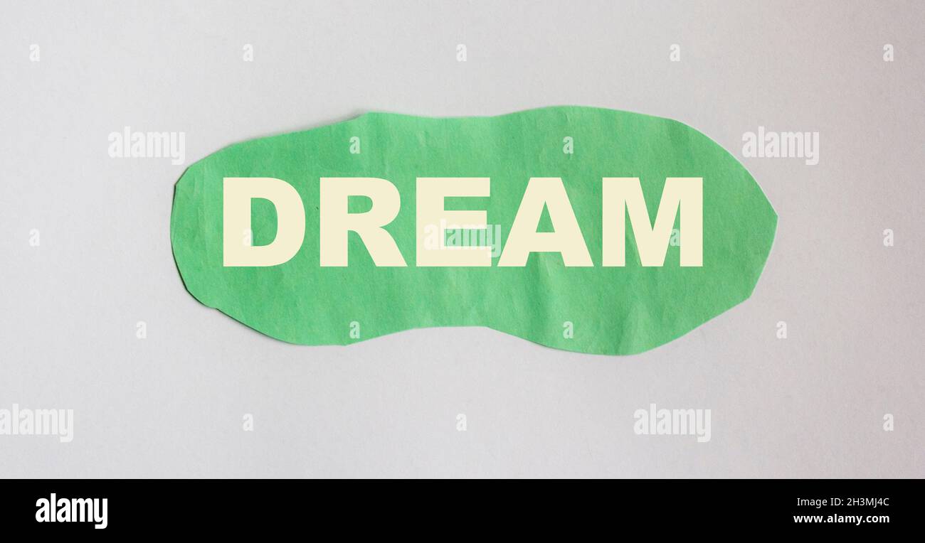 Dream, word written on green scrap of paper and blue background Stock Photo