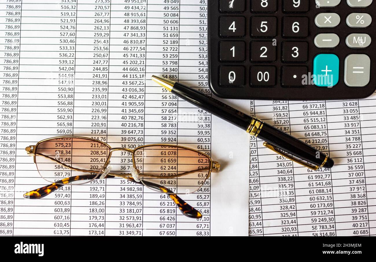 A pile of bills, a pen, glasses and a calculator on the table. Stock Photo