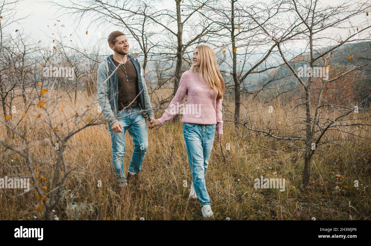 Man and woman walking together in nature outdoors. Two people in love are walking along the hillside holding hands Stock Photo