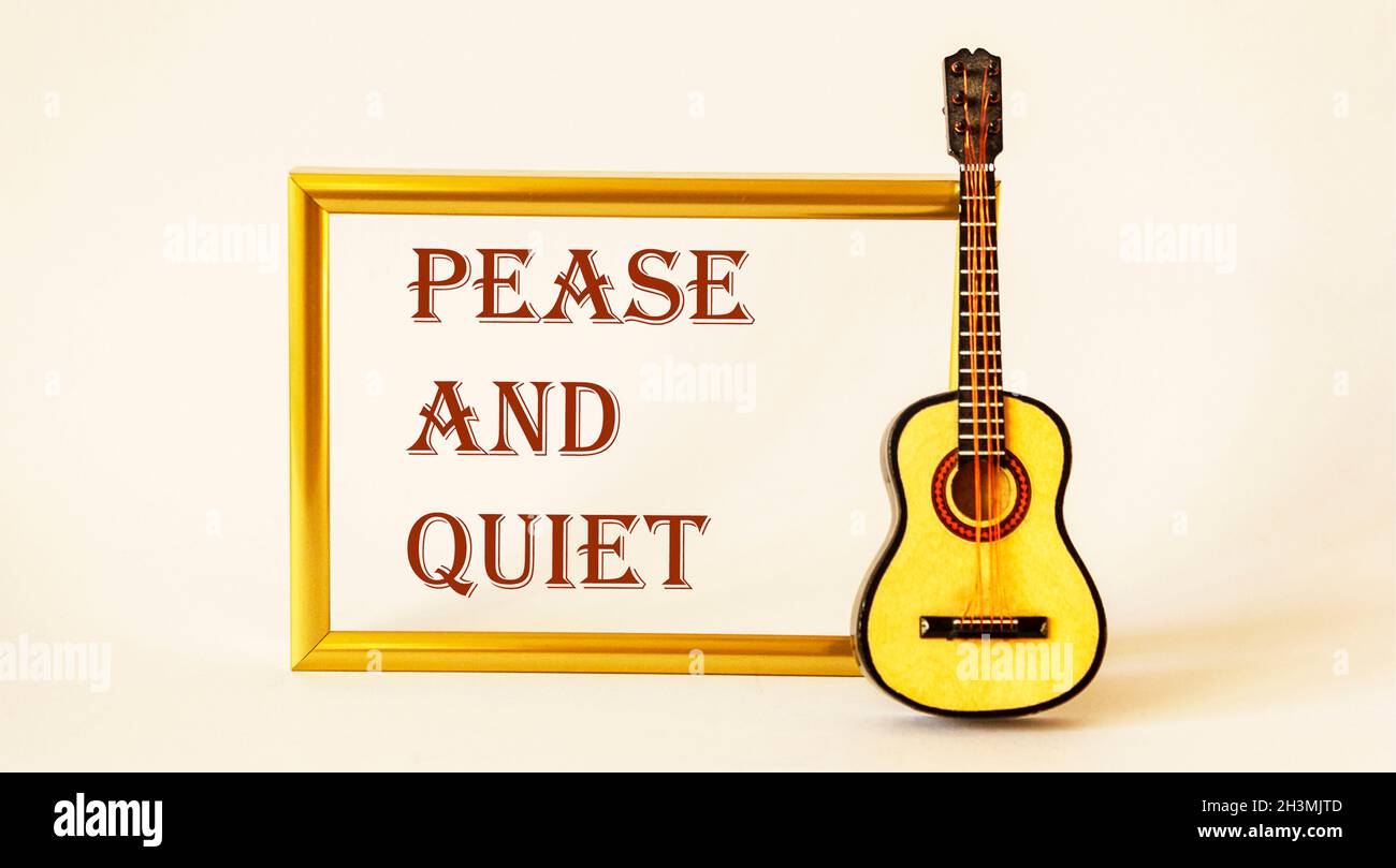 Pease and quiet , the text is written in a gold frame on a white background. Guitar is nearby. Stock Photo