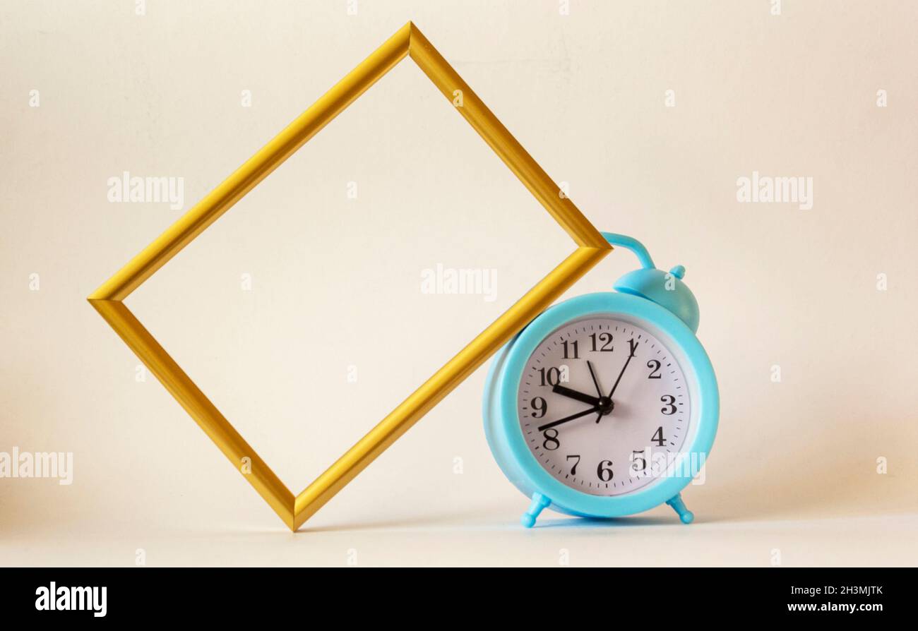 A blue alarm clock is placed on a white background with a frame for recording or photograph. Time management concept Writing notes at important moment Stock Photo