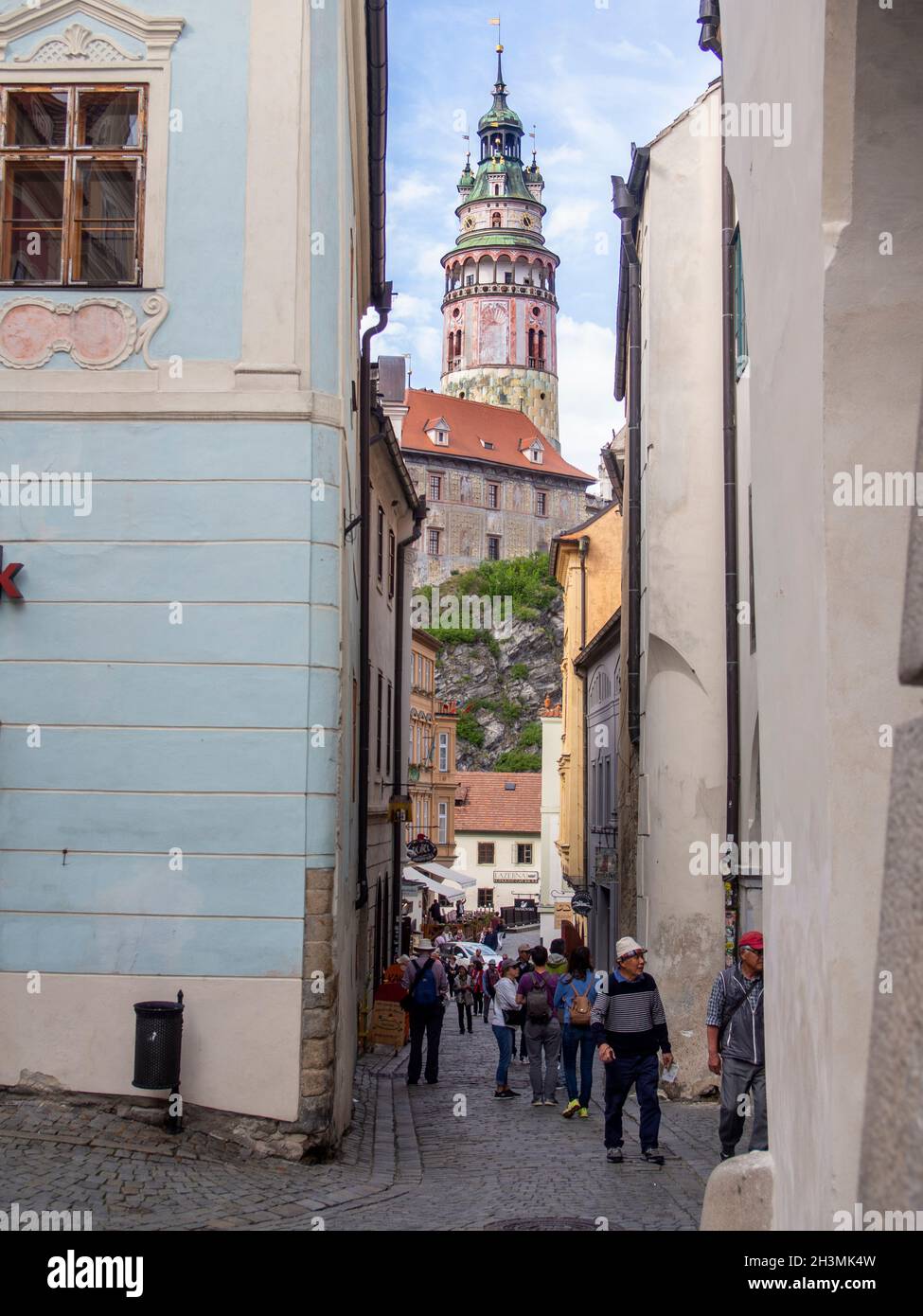 Český Krumlov Castle Tower framed by the narrow streets of the town: This high round renaissance tower dominates the skyline in the small town of Český Krumlov. Fresco paintings decorate its facade. Stock Photo