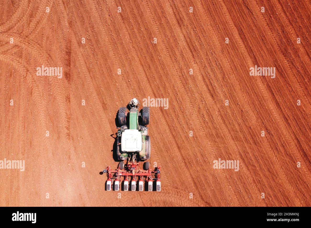 Farmer seeding, sowing crops at field with tractor. Sowing is the process of planting seeds in the ground as part of agricultura Stock Photo
