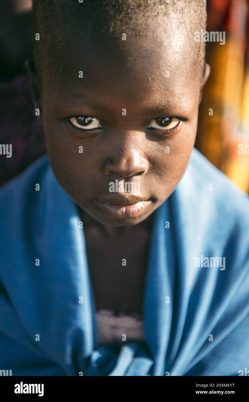 BOYA TRIBE, SOUTH SUDAN - MARCH 10, 2020: Child wrapped in blue cloth looking at camera while living in Boya Tribe village in So Stock Photo