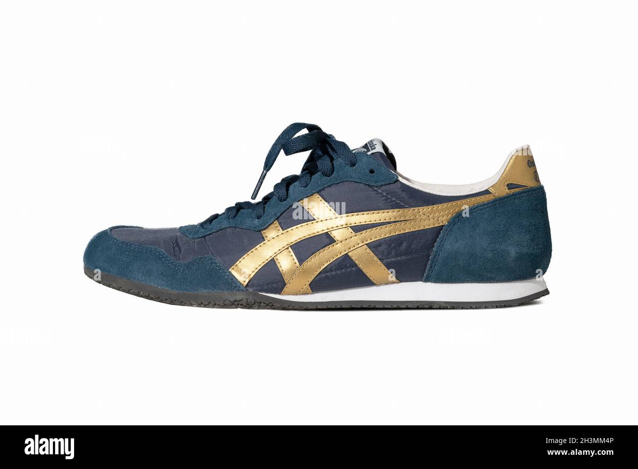 Blue sneakers of Asics brand. Stylish lace-up shoes for warm weather and a fitness hall. Blue suede shoes with gold accents cut Stock Photo