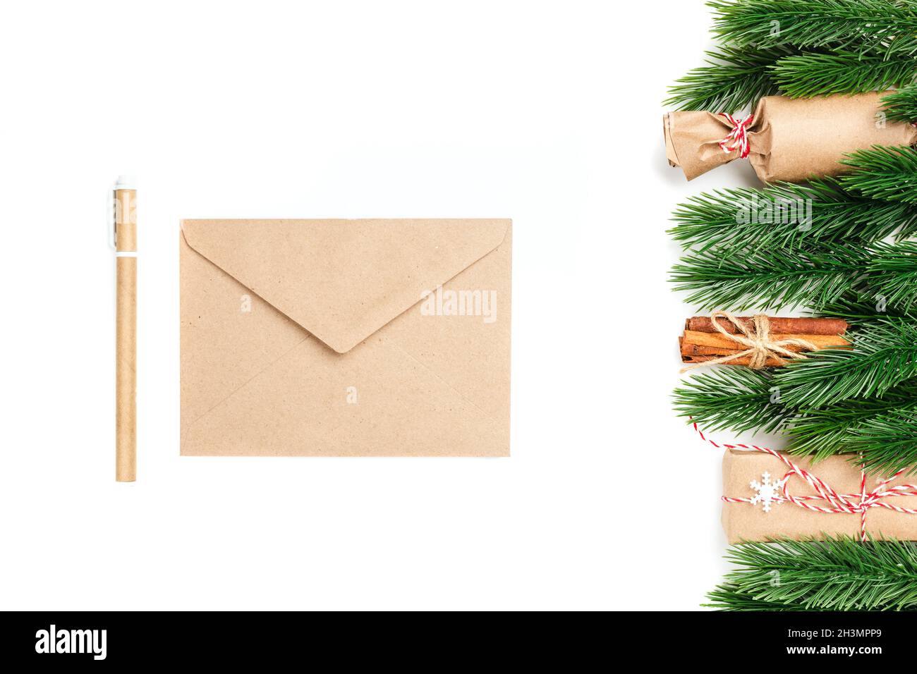 mock-up of craft envelope and craft pen with frame of pine branches and gift boxes on white isolated background with copy space Stock Photo