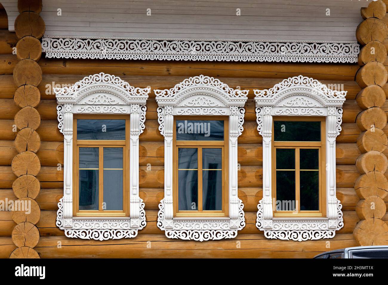 This is architectural fragment of wooden house in Vologda with carved patterns window decorations and cornices. Stock Photo