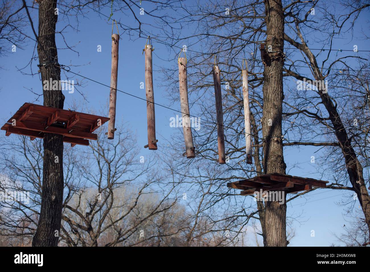Children's attraction in forest. Wooden suspension bridge between trees, attached sticks on tree for signal Stock Photo