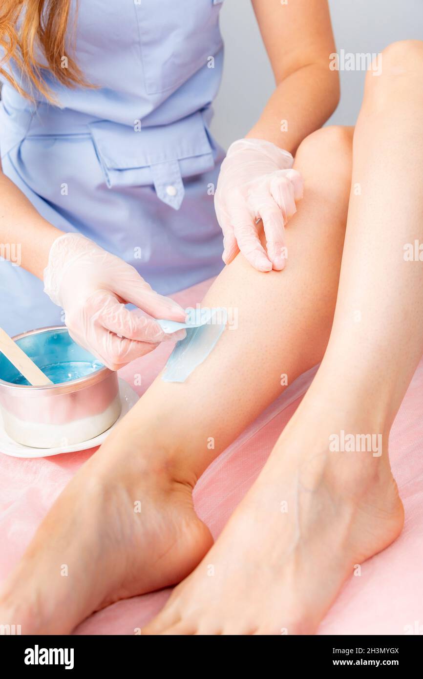 Sugar and waxing depilation of the feet in the beauty salon. Rid of hair on the legs. Sugaring. Master cosmetologist removing ha Stock Photo