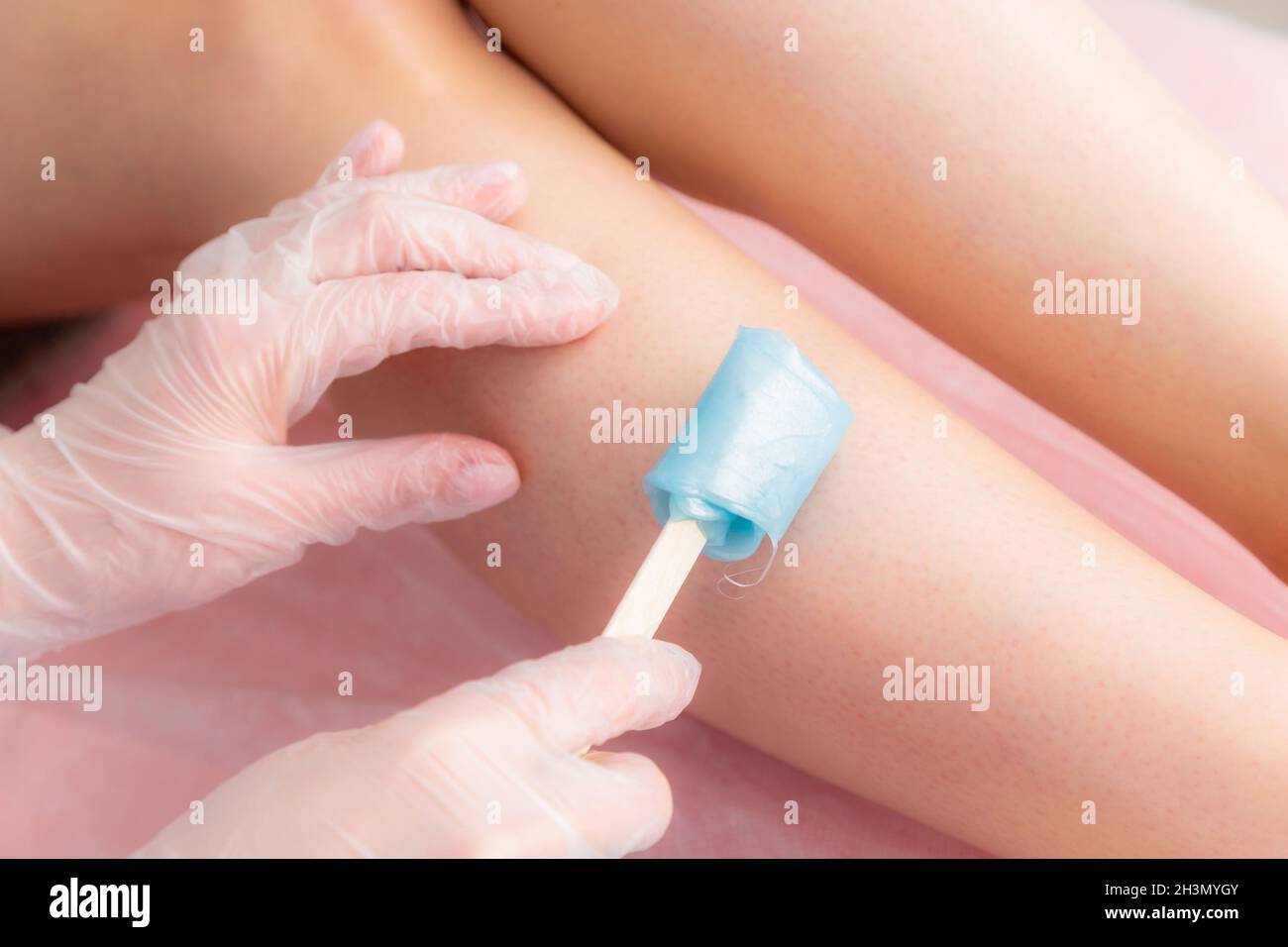 Sugar and waxing depilation of the feet in the beauty salon. Rid of hair on the legs. Sugaring. Master cosmetologist removing ha Stock Photo