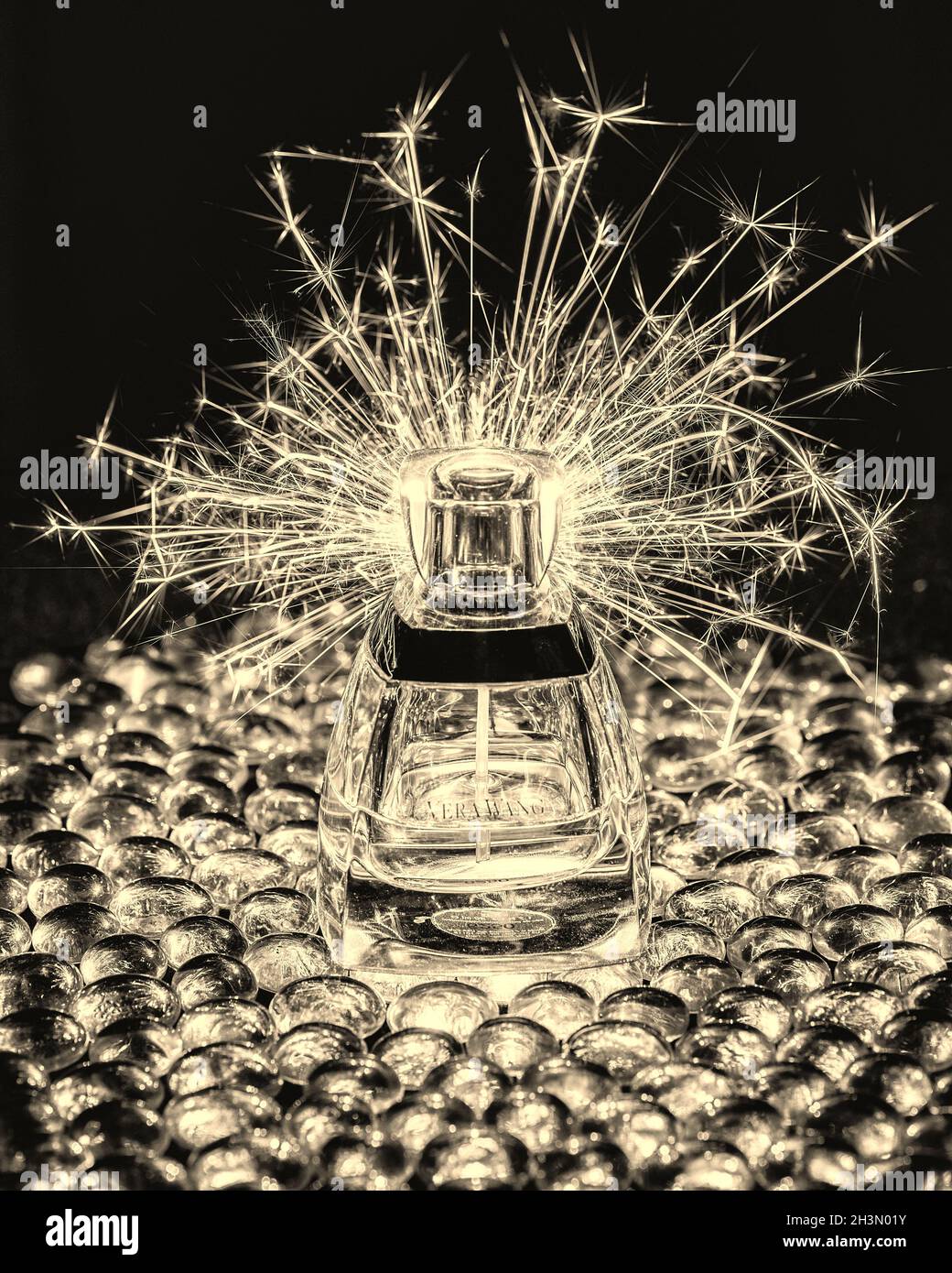 A lit sparkler throwing sparks over a 'Vera Wang' perfume bottle