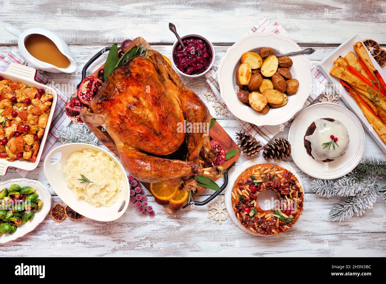 Traditional Christmas turkey dinner. Above view table scene on a rustic white wood background. Turkey, potatoes and sides, dressing, fruit cake and pl Stock Photo