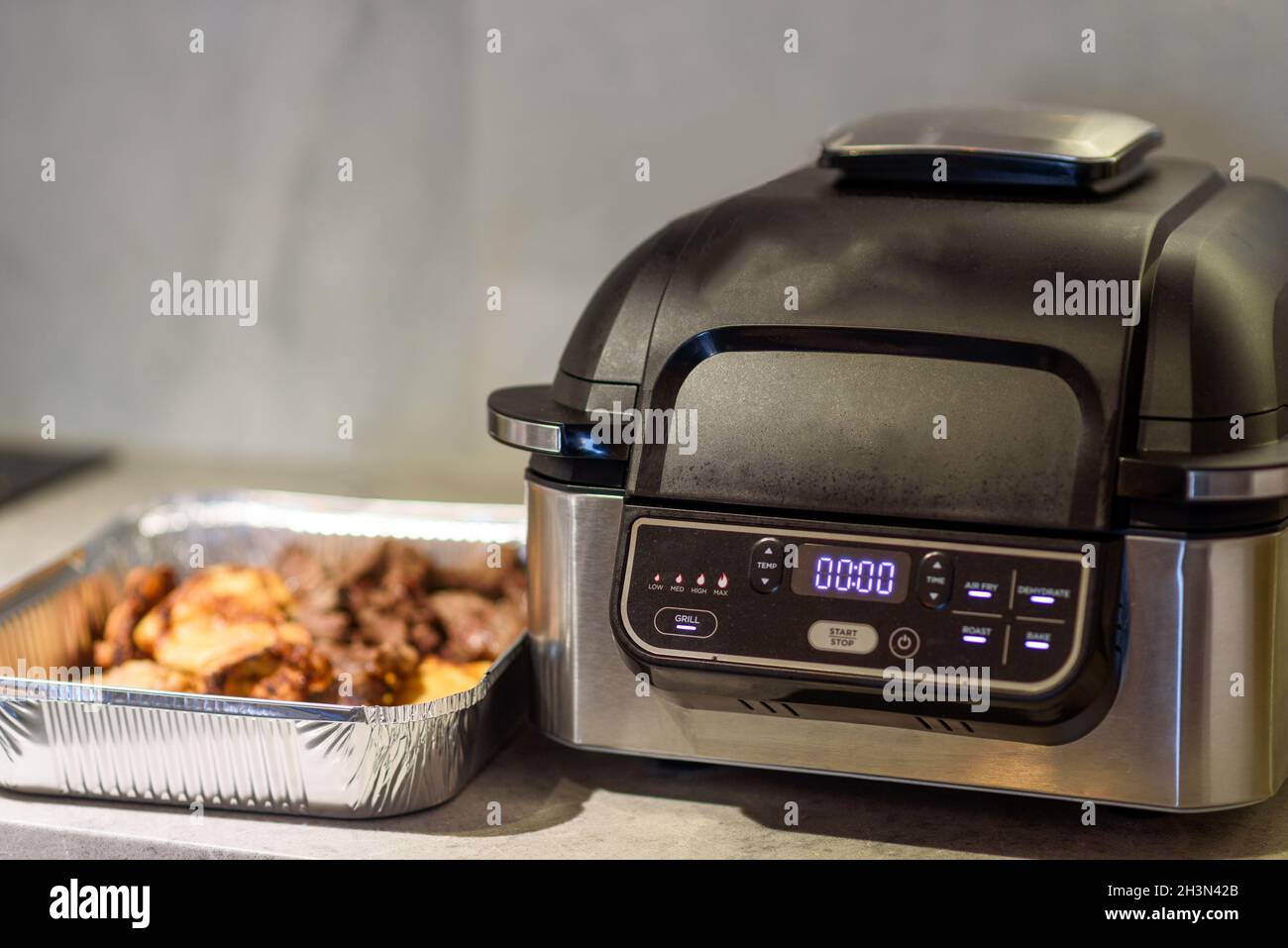 Air fryer in kitchen. Cooking meat with spices in an air fryer Stock