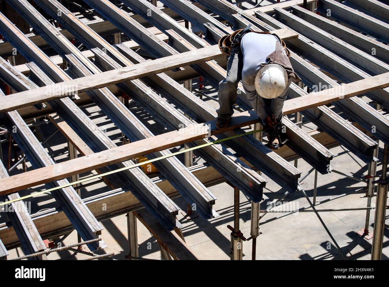 Construction worker aligns structural Ibeams for plywood sheathing
