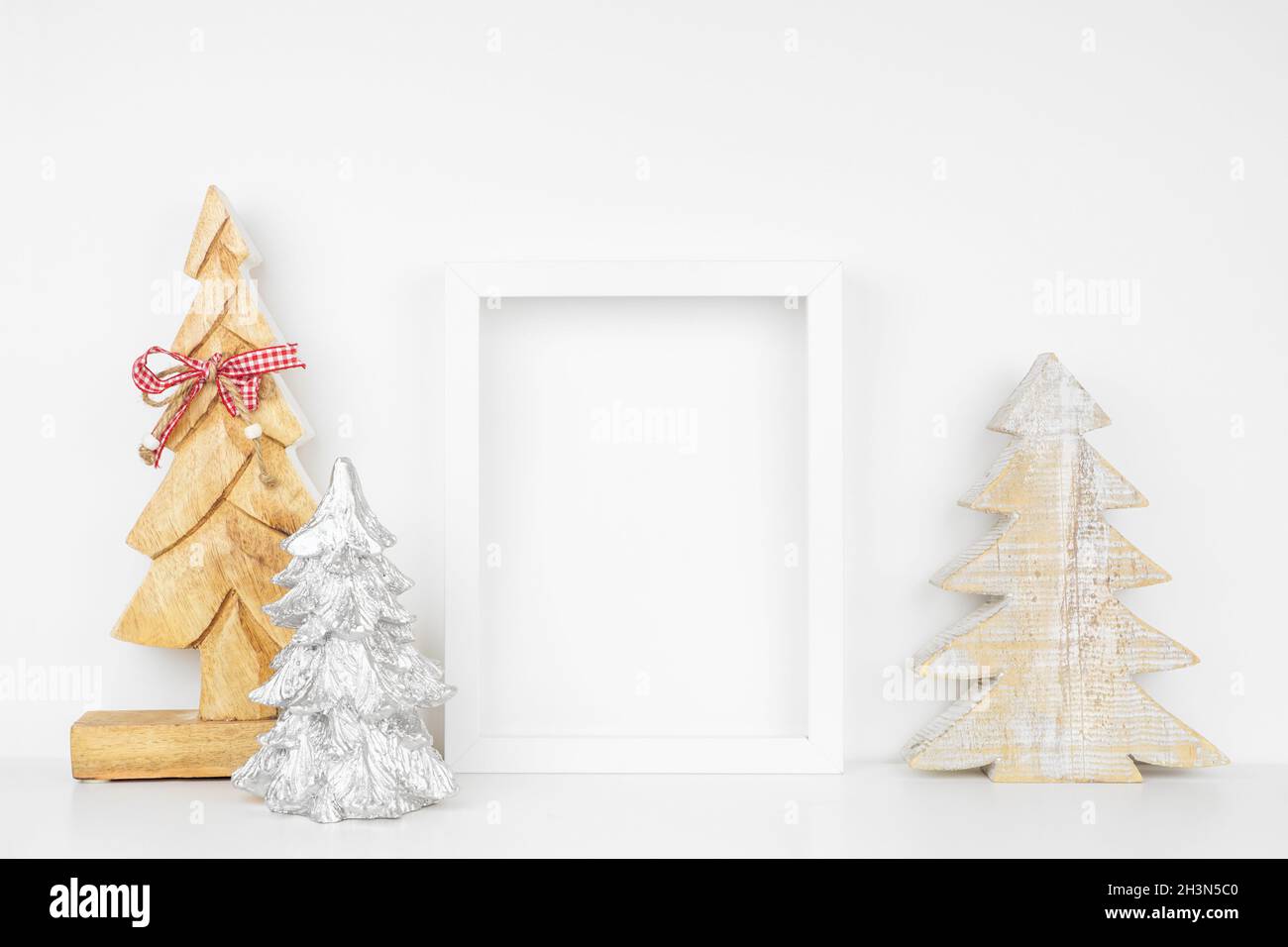 Mock up white frame with wooden Christmas tree decorations on a shelf ...