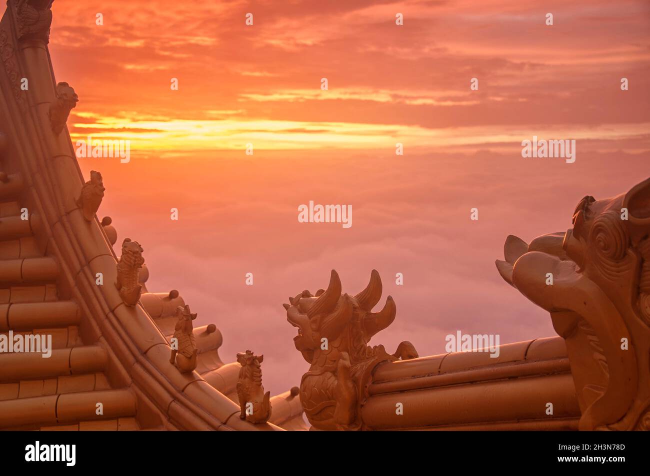 Small mythical creatures atop the buddhist golden hall as the sun rises on emeishan in sichuan province china. Stock Photo