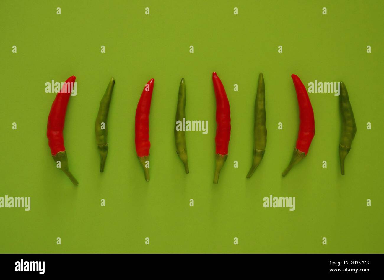 Composition of hot, green and red chillies on a green background. Stock Photo